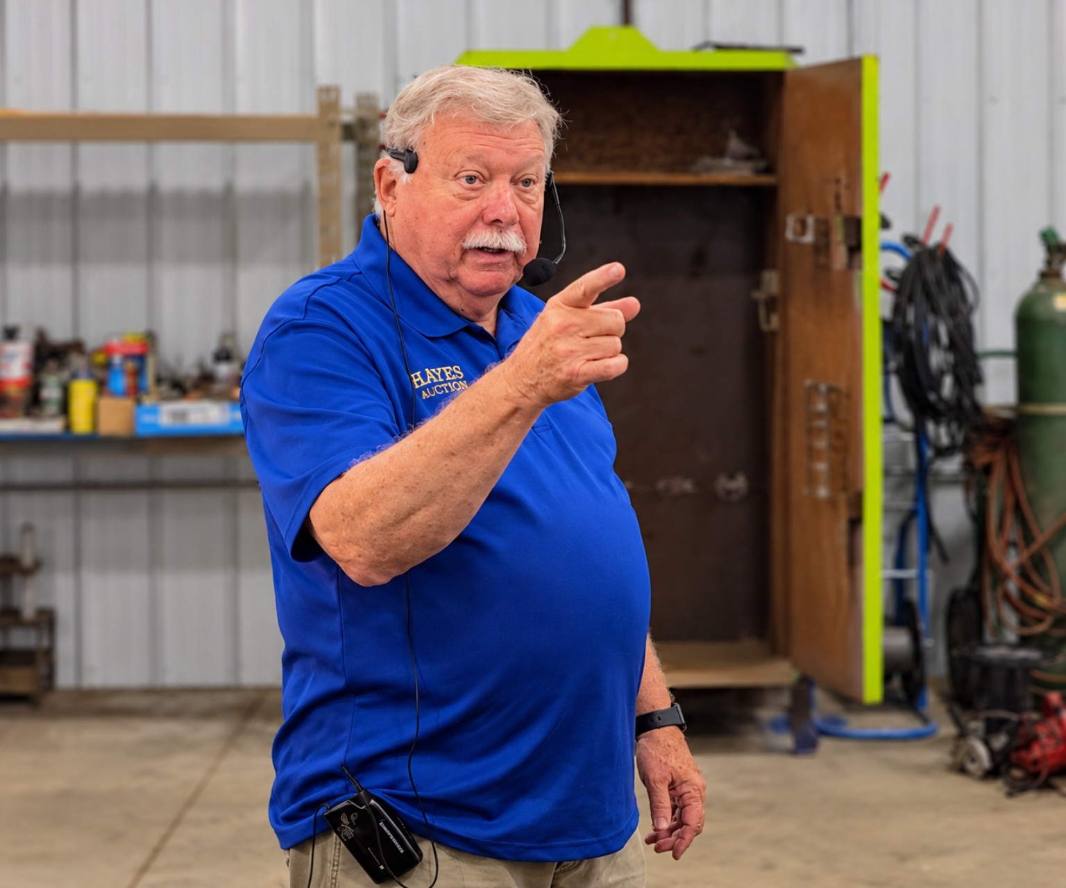 David Hayes auctioneering in his blue Hayes Auctions polo, wearing a headset and pointing toward a bidder